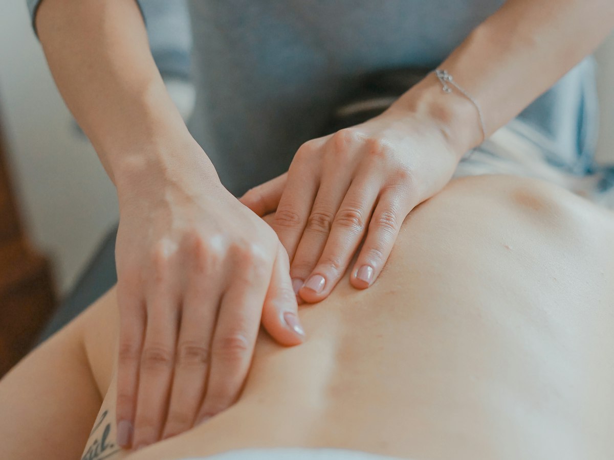 A practitioner's hands massaging a person's lower back