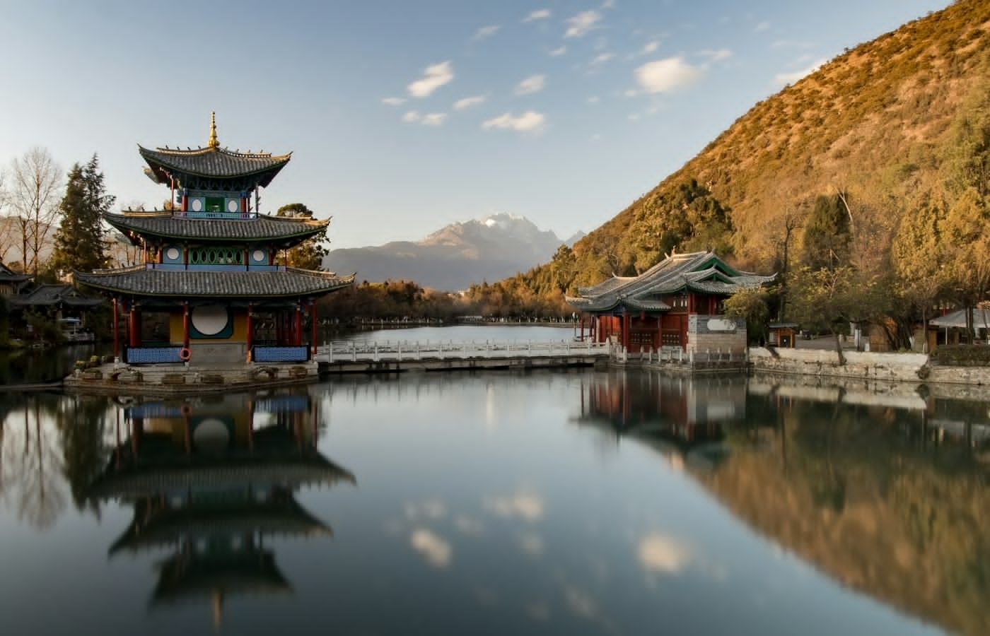 A pavilion reflected in a still lake with hills behind